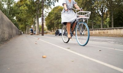 A cyclist in a grey dress on a bike lane beside a Paris street