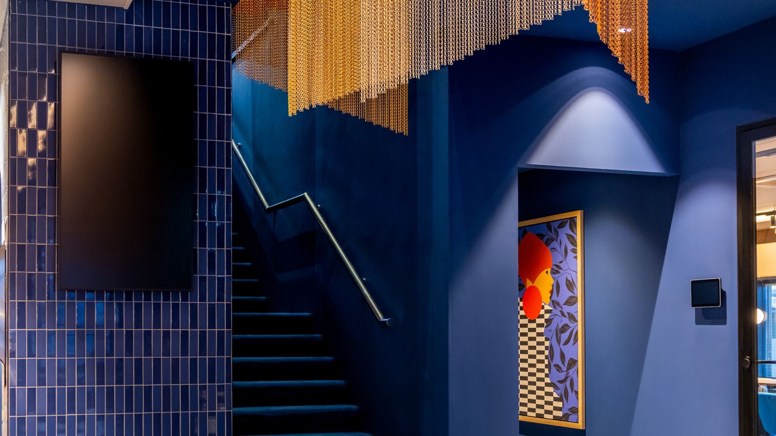 Hall de l’hôtel TRIBE Hotel Den Haag Centraal, aux murs bleus et décoré avec des oeuvres d’art