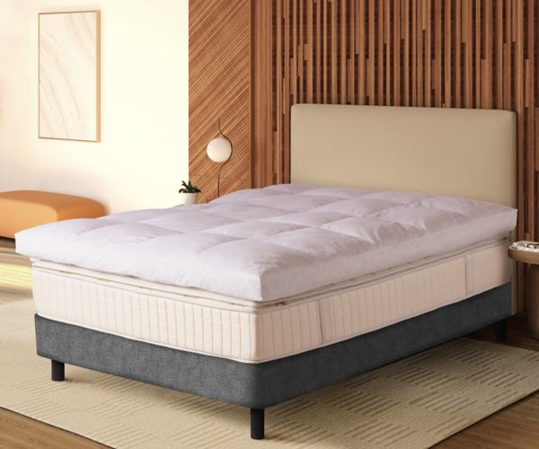 Mövenpick quilted white mattress topper on a bed in a modern bedroom setup