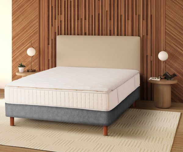 Mövenpick signature hotel bed with integrated mattress topper and grey base in front of a wooden headboard