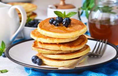 American pancakes topped with maple syrup and blueberries in a restaurant
