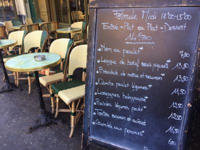 Menu écrit à la main sur une ardoise, placé sur la terrasse d’un bistrot parisien
