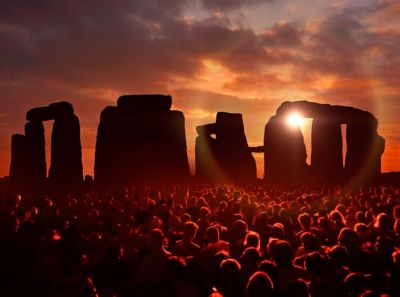 A sea of visitors against a sunset silhouette of Stonehenge in Wiltshire