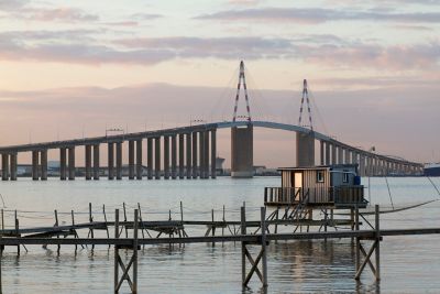 Cabane de pêcheur, ponton en bois et pont de Saint-Nazaire, sous un ciel nuageux au coucher du soleil