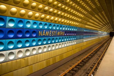 A Prague metro station tunnel with gleaming gold, violet and teal tiles