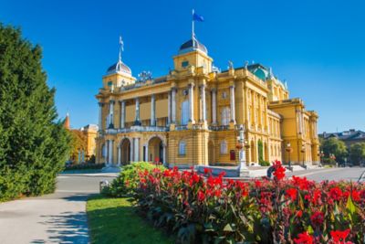 Impressive yellow façade of the Croatian National Theatre in Zagreb, with sculpted domes and Corinthian columns