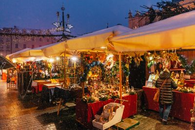 Stände mit weihnachtlicher Dekoration auf dem Weihnachtsmarkt von Krakau in der Dämmerung