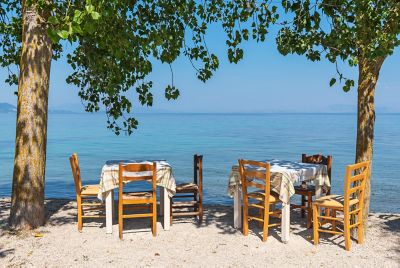 Tables and chairs at a taverna facing the Ionian Sea on Corfu island, Greece