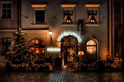 Weihnachtlich geschmücktes Restaurant in Krakau bei Nacht, mit dekoriertem Weihnachtsbaum