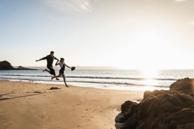 Un couple court joyeusement sur une plage lors d’un week-end en amoureux en Bretagne