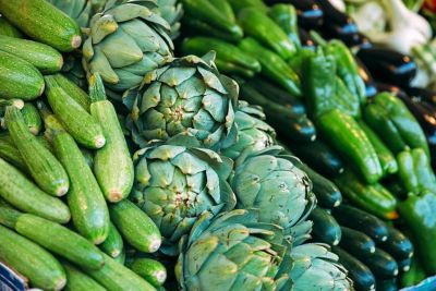 Courgettes, artichauts et poivrons verts disposés sur un étal de marché