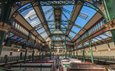 Stalls in Kirkgate Market in Leeds under a curved, iron-and-glass roof
