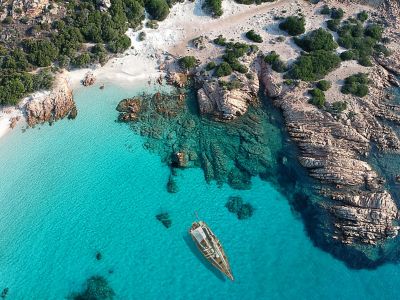 A sailboat in a turquoise lagoon in Maddalena Archipelago National Park, Olbia