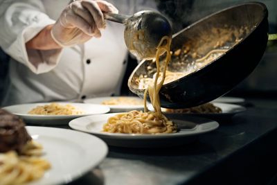 A chef plating dishes of spaghetti at an Italian restaurant