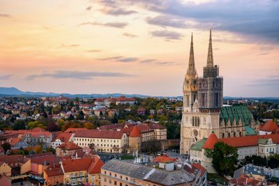 The twin spires of Zagreb Cathedral surrounded by the city's red rooftops against a golden sunrise