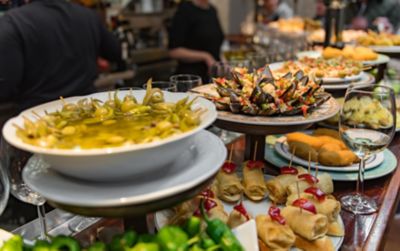 Una barra de bar con una variedad de pintxos y tapas, como aceitunas y mejillones