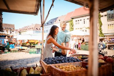 Un couple en vacances qui achète des produits du terroir sur un marché de producteurs, un matin d’été