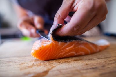A chef removing the skin from a fillet of salmon, a common French seafood dish