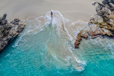 A mindful traveller emerging from azure waters onto a golden beach