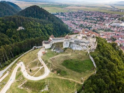Medieval Râșnov Fortress with stone walls on a hill overlooking forests and a village