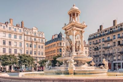 Fuente monumental en la Place des Jacobins, rodeada de edificios clásicos bajo un cielo despejado