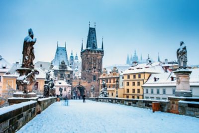A snow-covered Charles Bridge, lined with statues, on a quiet Prague morning