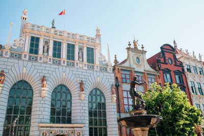 The elegant white façade of Artus Court, by the iconic Neptune's Fountain, in Gdańsk