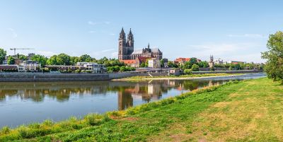 Der Dom von Magdeburg mit der Elbe und grünen Wiesen im Vordergrund