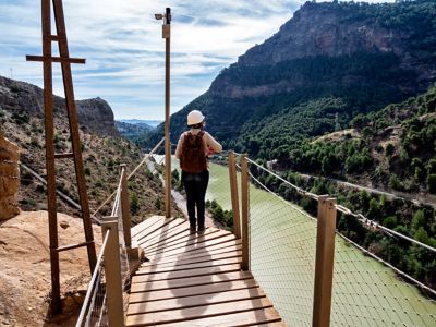 Persona caminando por las pasarelas de madera suspendidas a gran altura del Caminito del Rey