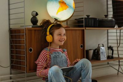 A delighted child listening to a podcast in preparation for a holiday