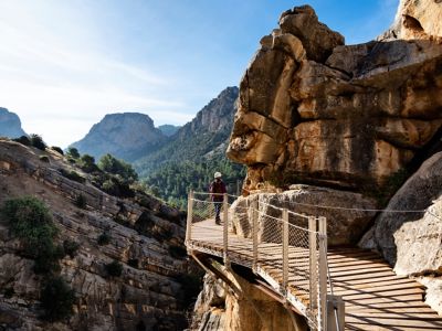 Persona caminando por la pasarela del Caminito del Rey adosada a la roca en el interior de un cañón
