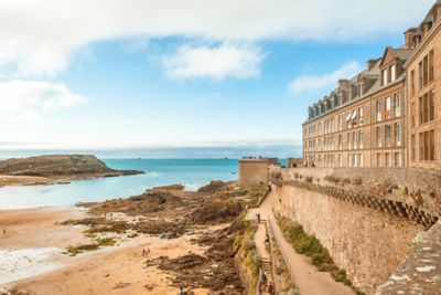 Vacanciers qui se promènent sur la plage de Saint-Malo à marée basse, au pied des remparts