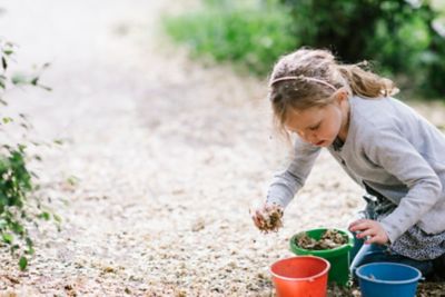 A child collecting leaves outdoors, a great sensory idea while travelling