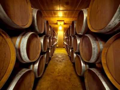 Un pasillo creado entre las hileras de toneles de vino en el sótano de una bodega