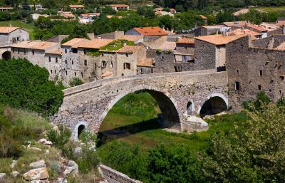 Weathered stone houses and an arched stone bridge in Lagrasse village, Occitanie