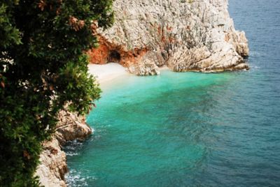 Secluded beach in Croatia with turquoise waters, a quiet shore and rugged rocky cliffs