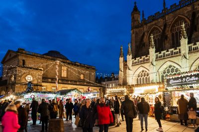 Mercado navideño concurrido frente a la Abadía de Bath por la noche
