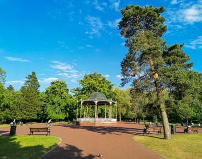 The bandstand framed by tall trees at West Park in Wolverhampton on a sunny day