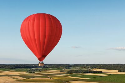 Montgolfière rouge en plein vol au-dessus des champs, dans la vallée de la Loire