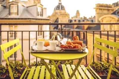 A traditional French breakfast tray set on a balcony overlooking Paris