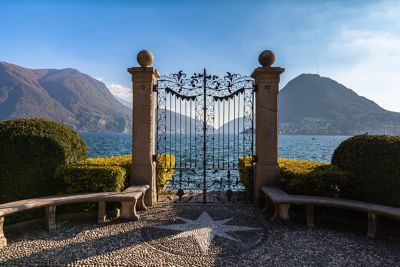 Verziertes Eisentor im Parco Ciani in Lugano, mit Blick auf den See und die Berge