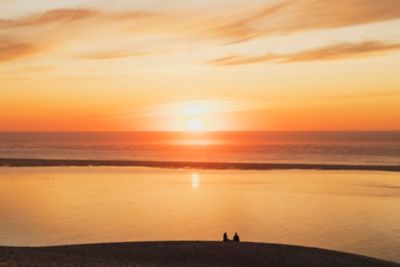 La silhouette d’un couple qui pique-nique au bord de la mer près de la dune du Pilat, au coucher du soleil