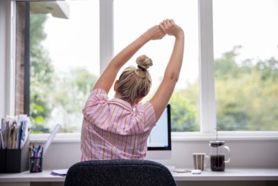 A desk worker practising active sitting by stretching both arms overhead