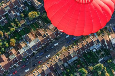 Roter Virgin-Heißluftballon schwebt tief über einer Wohnstraße in Bristol
