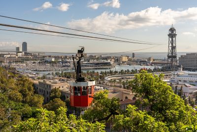 Panorámica de la cabina roja del teleférico de Montjuic y la torre de acero del puerto de Barcelona
