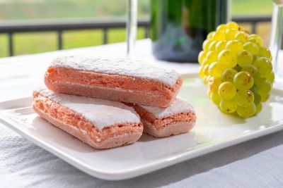Biscuits roses de Reims, disposés sur une assiette blanche avec une grappe de raisin, sur la terrasse d’un café
