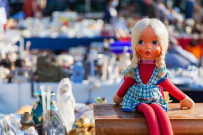 Poupée vintage posée sur une boite en bois dans une brocante