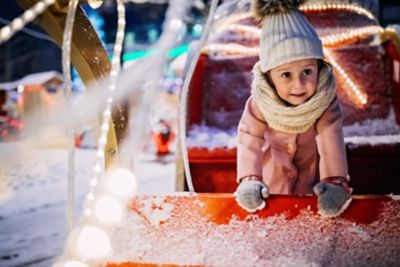 Fillette qui pose pour une photo dans un traineau de Noël décoratif, lors d’une soirée enneigée