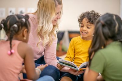 Three children and an adult sitting on the floor enjoying a story-telling session