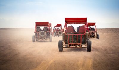 Mehrere rote Quads fahren durch die staubige ägyptische Wüste